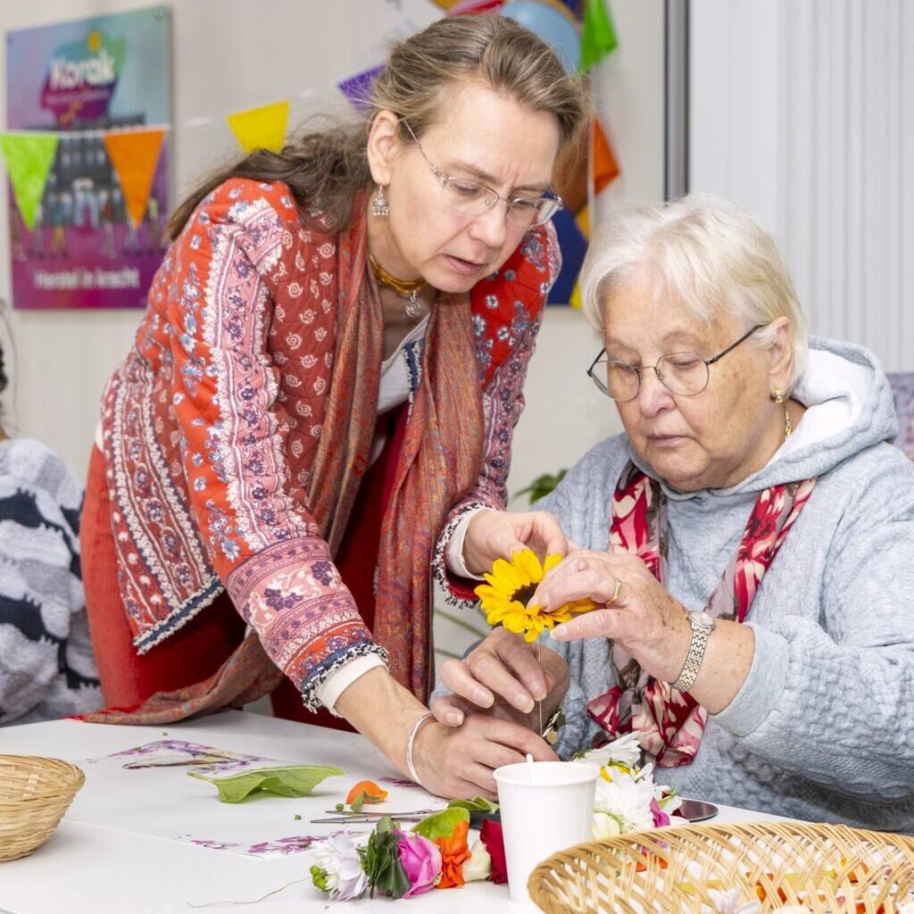 Shakti Bloemenmala Tonny Bol speciale workshop bloemenslingers maken eenjarig jubileum Korak Herstelacademie Heerde Tonny instrueert deelneemster