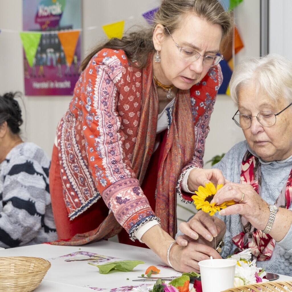Shakti Bloemenmala Tonny Bol helpen zonnebloem aanprikken cursist workshop bloemenslingers maken Herstelacademie Korak één jarig jubileum Heerde