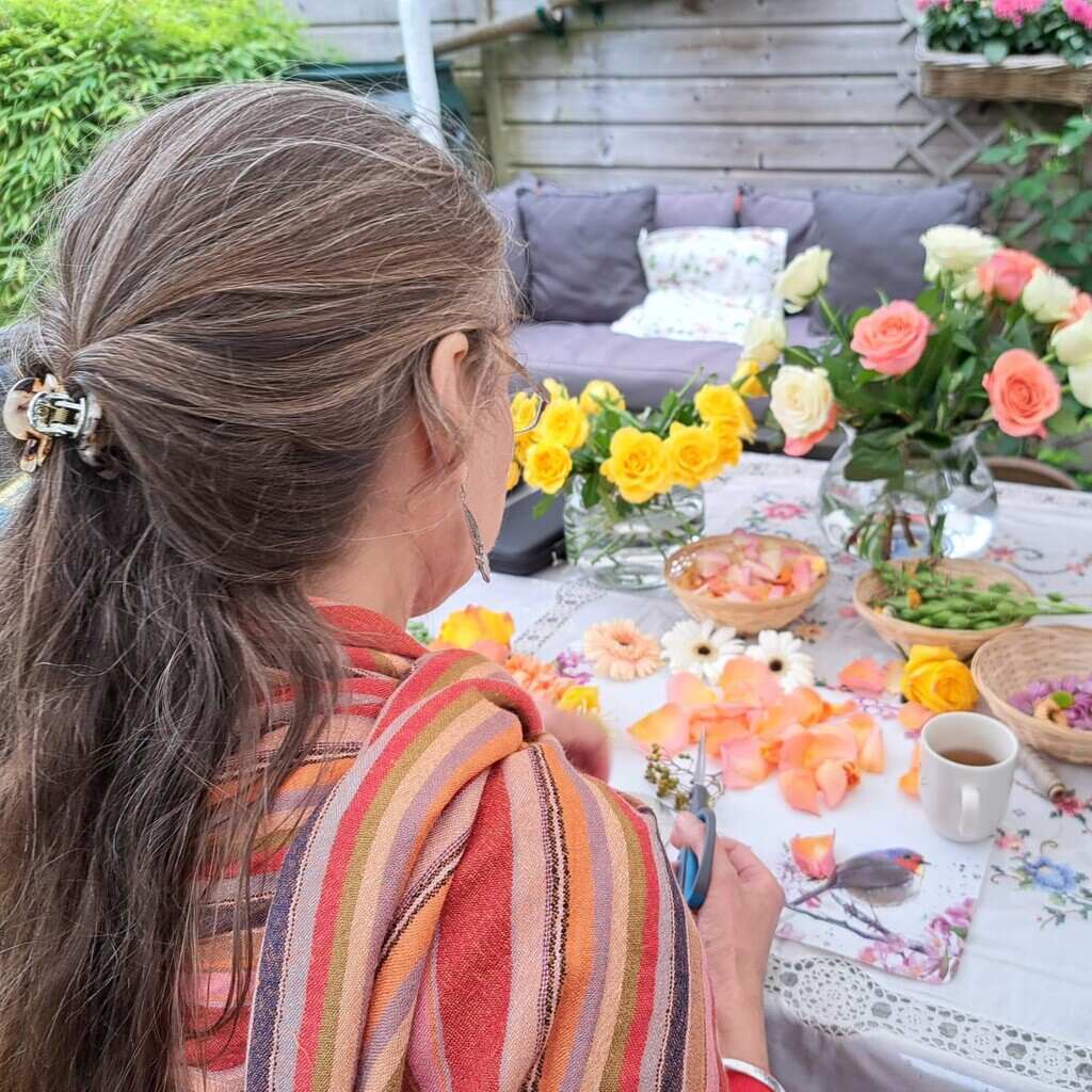 Shakti Bloemenmala Tonny Bol mala's maken tuin bloemenvaas gele witte rose rozen rozenblaadjes rieten mandjes gezellige tuinbank zomers buiten