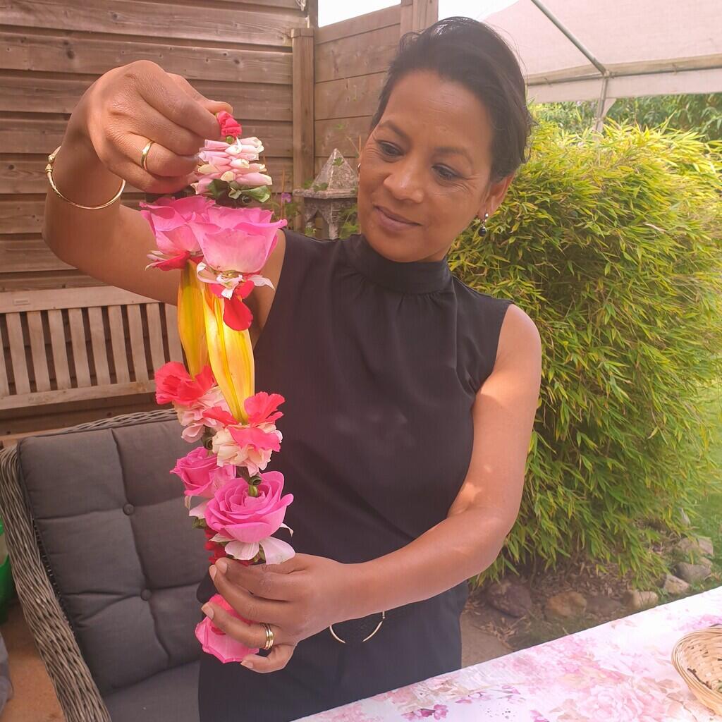 Shakti Bloemenmala Tonny Bol workshop cursist toont blij Indiase rozen bloemenslinger verse bloemen in tuin