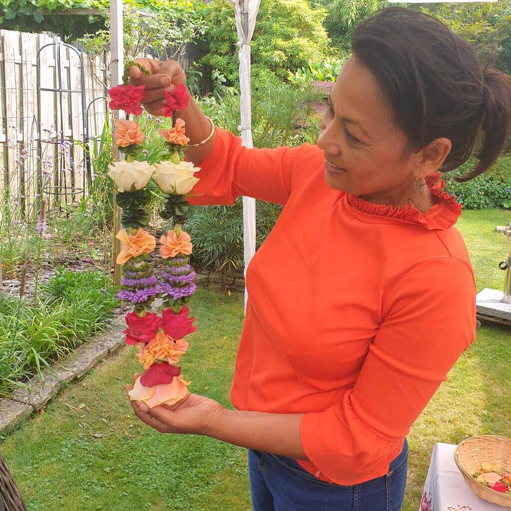 Shakti Bloemenmala Tonny Bol cursist toont blij resultaat mala les tuin Persoonlijk Trainings Traject workshops intuïtief bloemenslingers maken