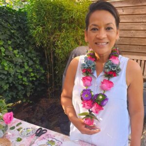 Shakti Bloemenmala Tonny Bol blije cursist toont bloemenslinger workshop bloemenslingers maken groene tuin tafel verse bloemen