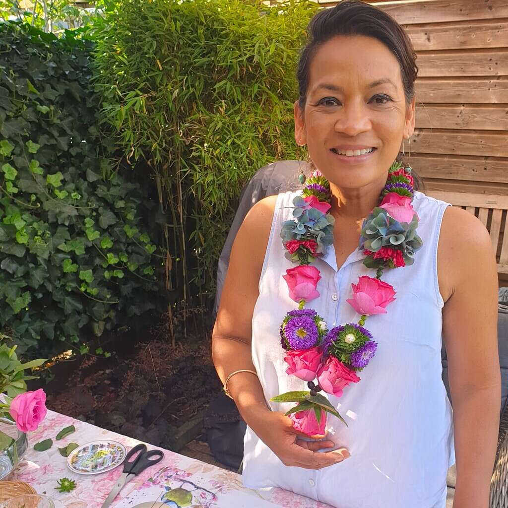 Shakti Bloemenmala Tonny Bol blije cursist toont bloemenslinger workshop bloemenslingers maken groene tuin tafel verse bloemen