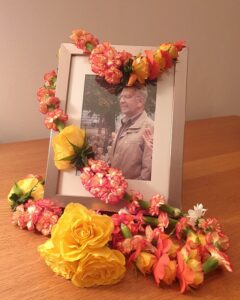 Shakti Bloemenmala, Tonny Bol, lange oranje gele gedenkmala om fotolijst gedrapeerd