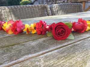 Shakti bloemenmala's Tonny Bol Grote rood met gele mala op tuintafel