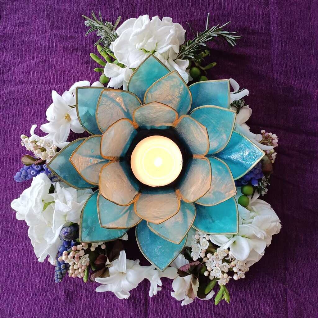 Shakti Bloemenmala Tonny Bol brandend blauw waxinelicht witte fleurige bloemenkrans paarse doek decoratief huisaltaar