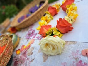 Shakti Bloemenmala, Tonny Bol, oranje, geel, witte bloemenkrans op tafel met bloemen en mandjes.