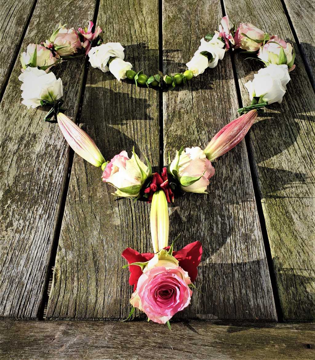 Shakti bloemenmala's Tonny Bol Mala met rozen en gesloten lelies in hartvorm op houten buitentafel