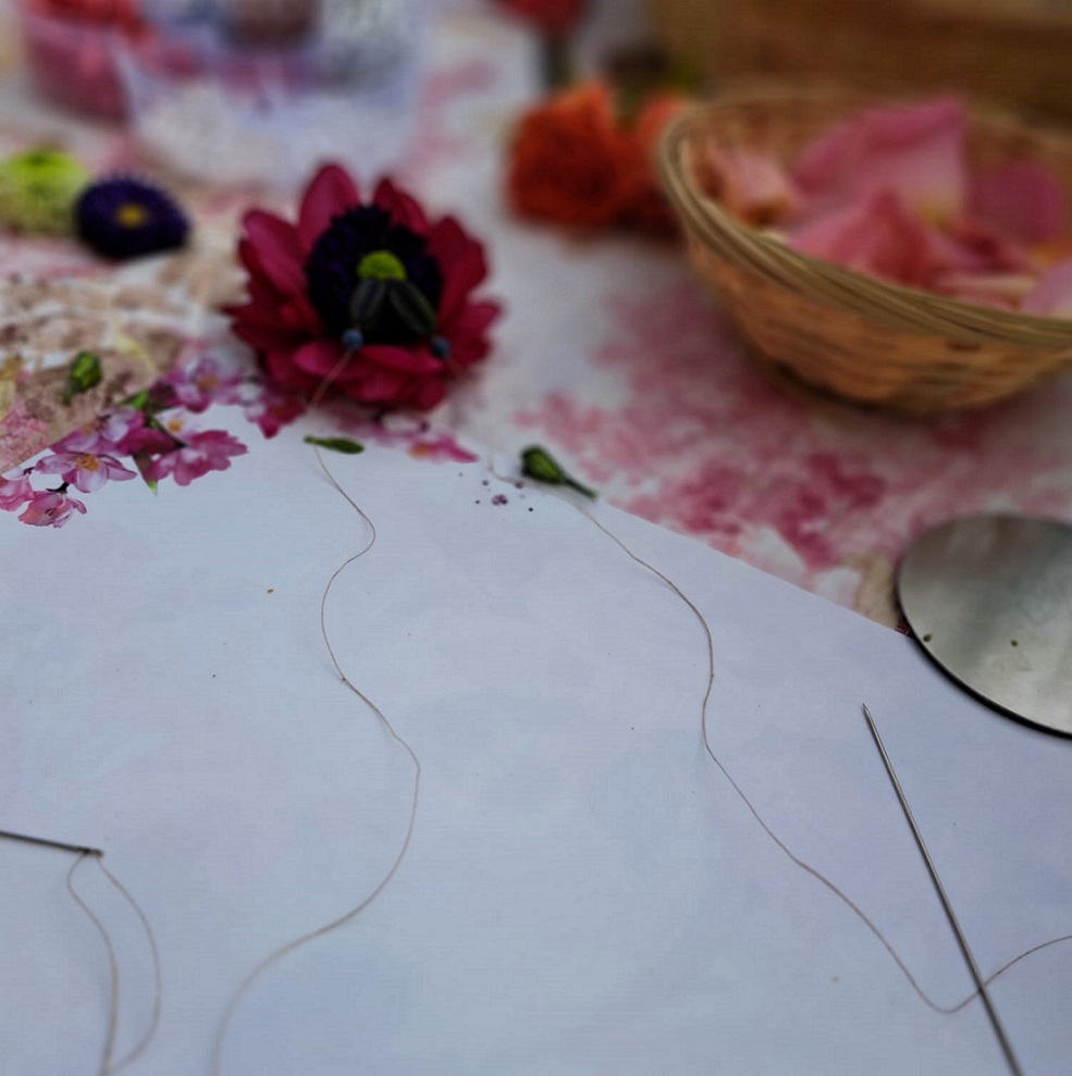 Shakti Bloemenmala, Tonny Bol, naald en draad, placemat, op tafel met enkele bloemen en bloemblaadjes in mandje