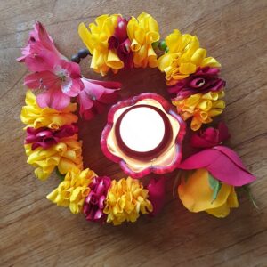 Shakti Bloemenmala, Tonny Bol, rose gele bloemenslinger om brandend waxinelicht op houten ondergrond